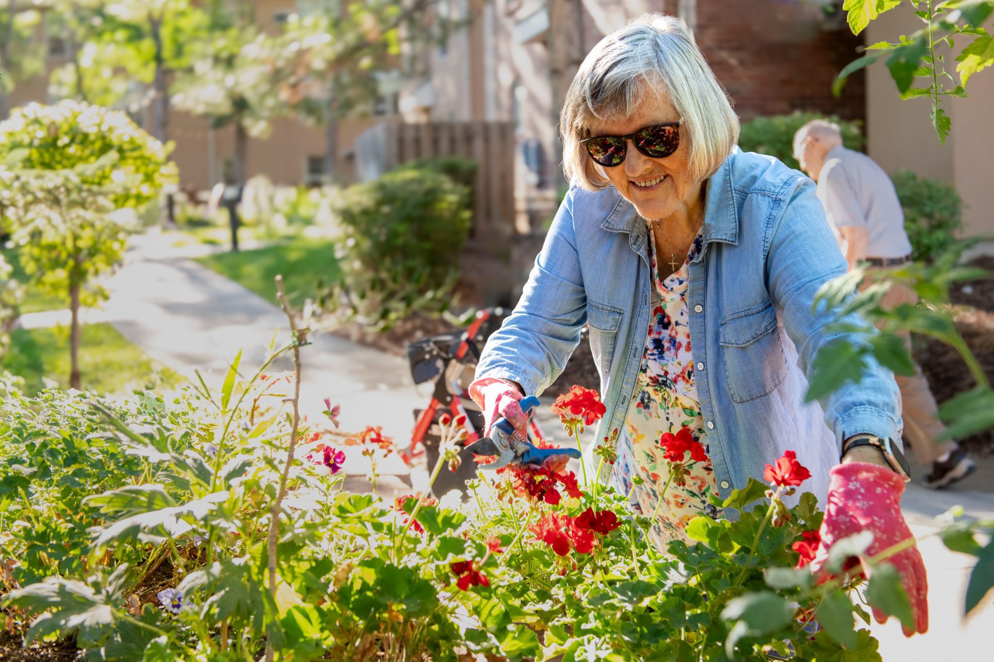 Someren Glen Senior Living Community in Centennial, CO - older woman pruning garden bed largelandscape